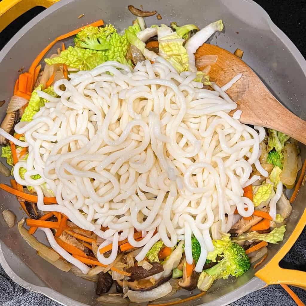 Adding the udon noodles to the dish.