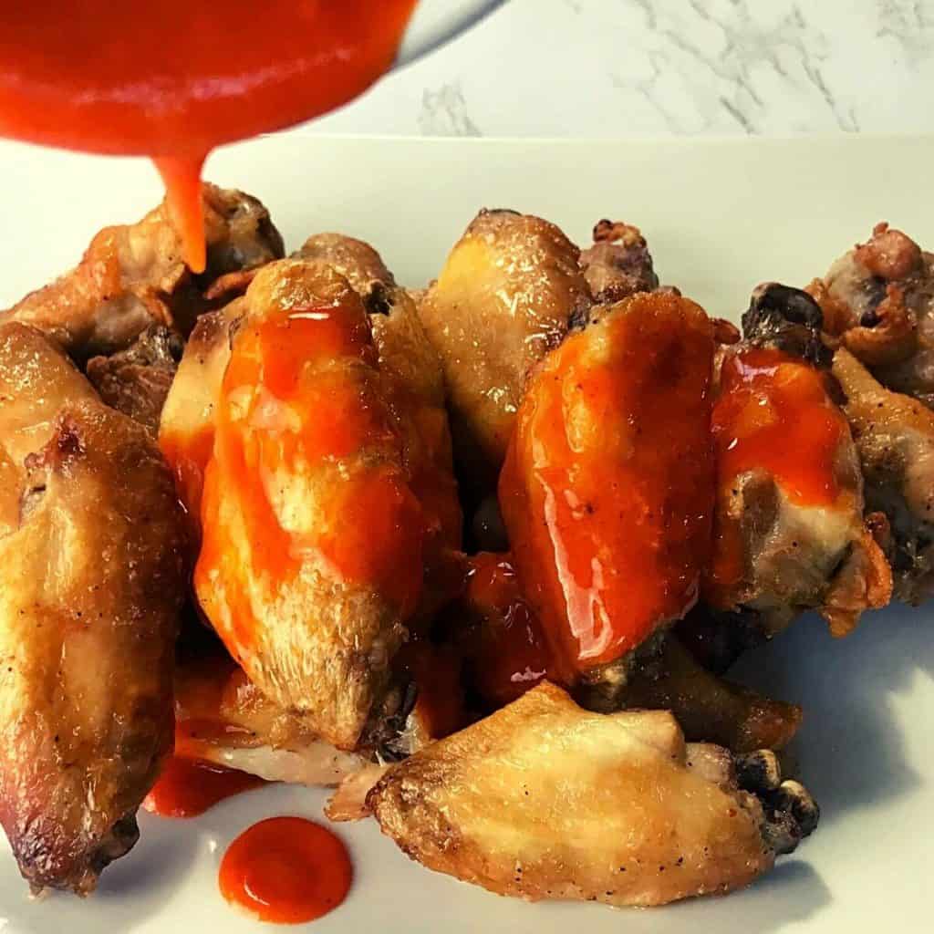 Coating chicken wings with buffalo sauce