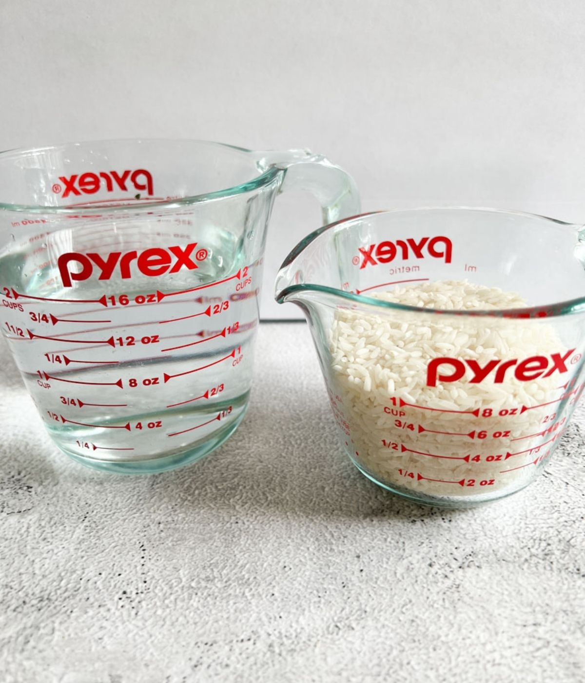 A cup of uncook rice and some water.