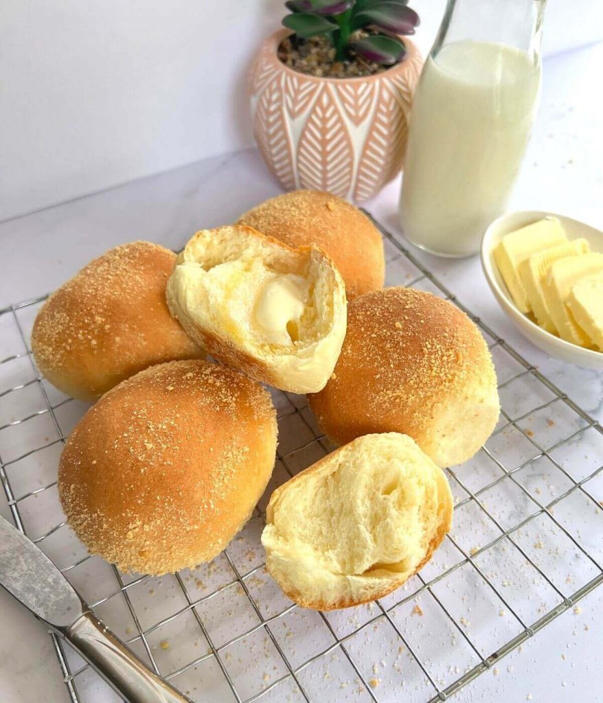 Pandesal with butter spread and milk on table