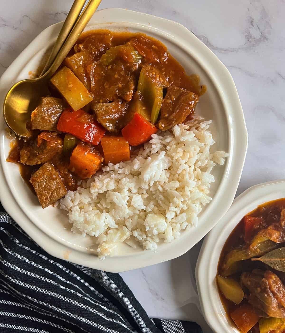 Beef mechado and rice on a plate.