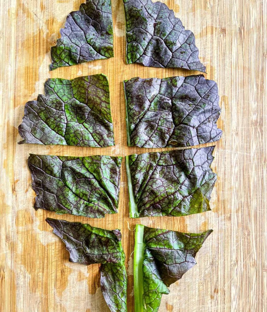 Chop mustard greens on a chopping board.