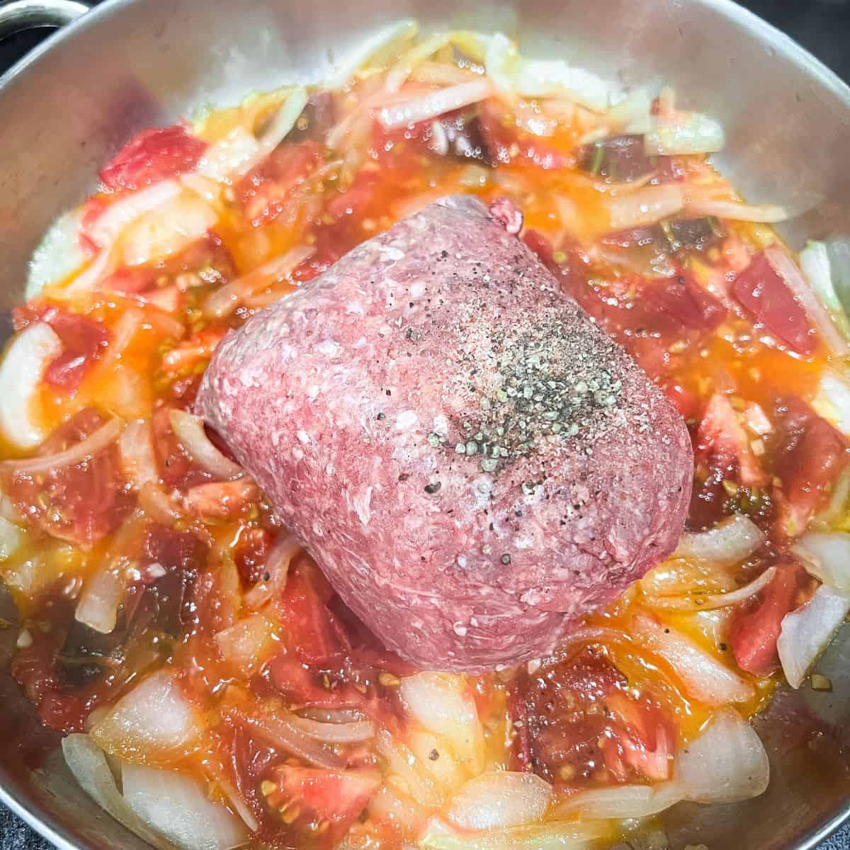 Adding meat and seasoning to the dish.