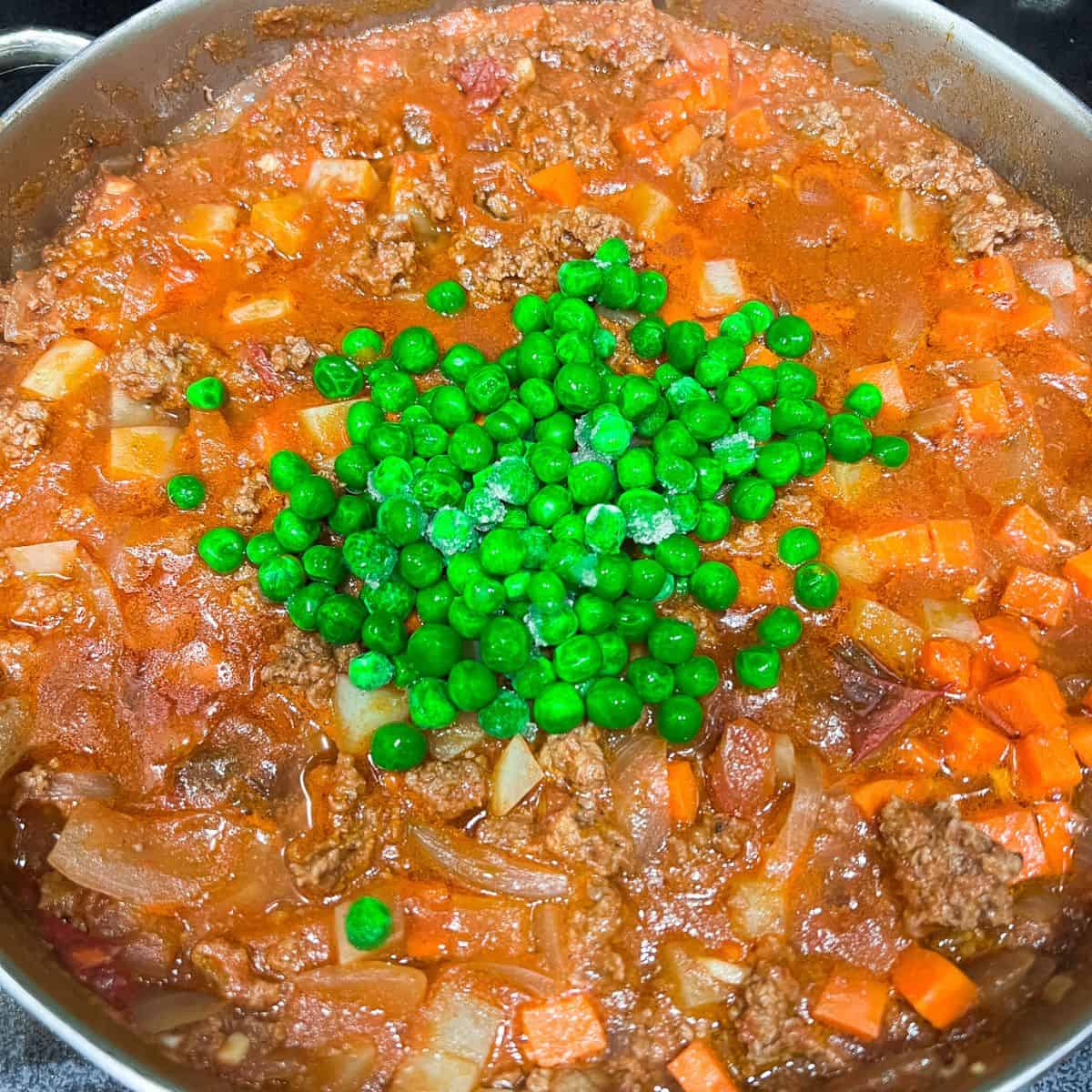 Adding green peas to the dish.
