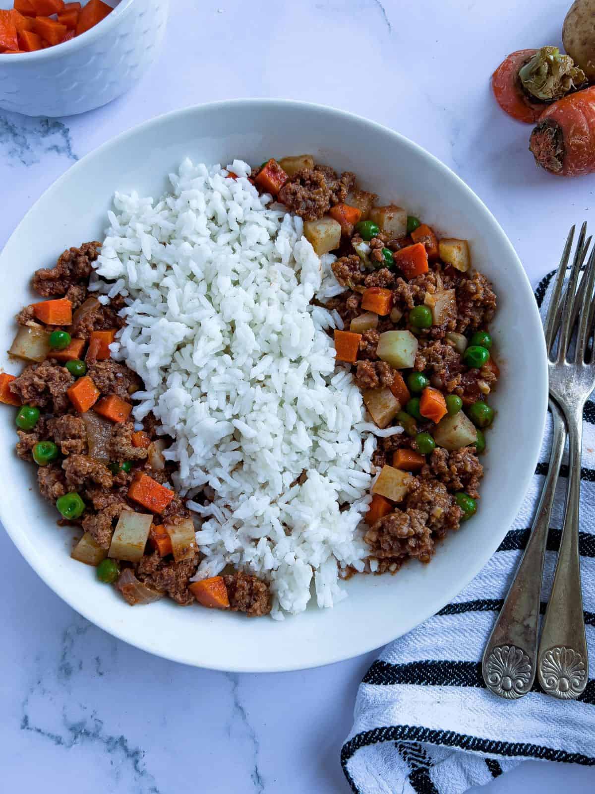 Beef giniling over rice on a bowl with utensils.