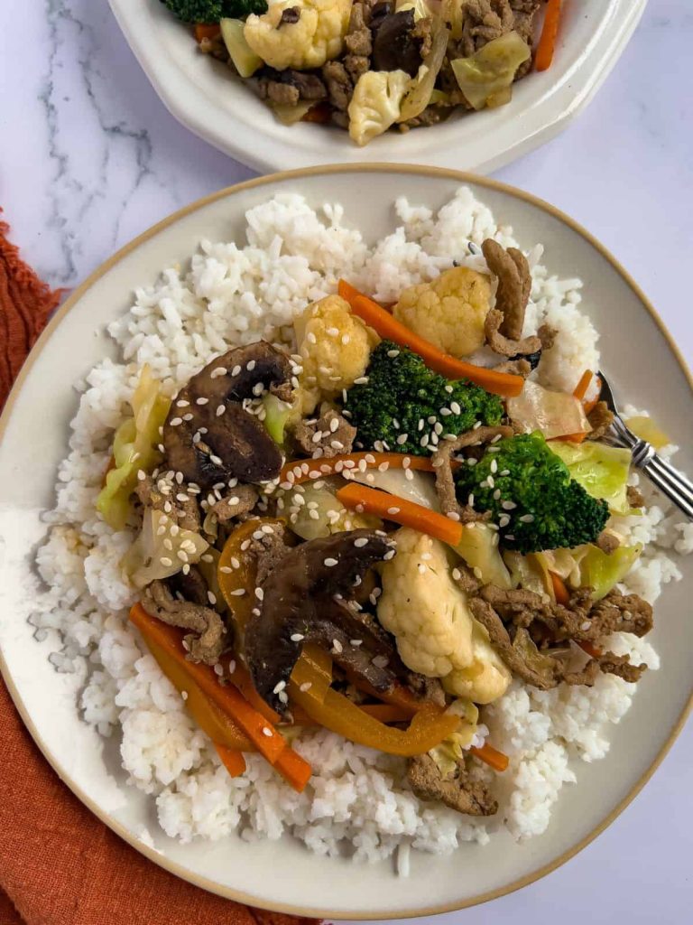 Ground turkey stir-fry over rice on a plate.