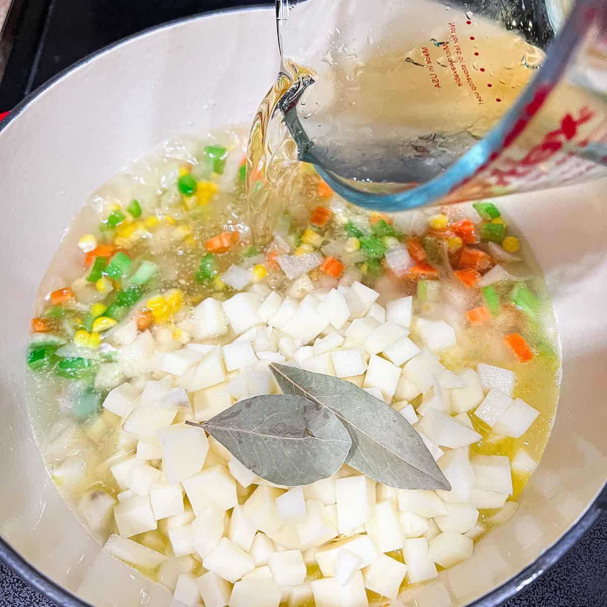 Pouring chicken broth into the dutch oven.