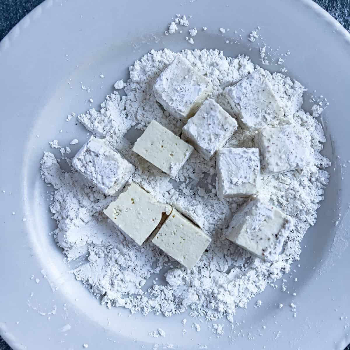 Coating the tofu in cornstarch, salt, and pepper.