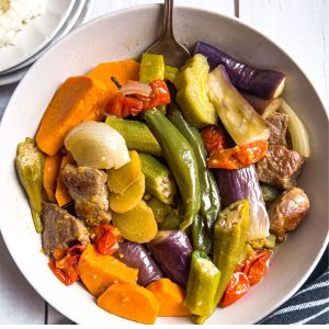 Pakbet in a plate with rice on the side.