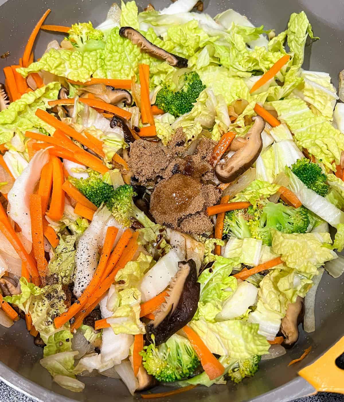Adding vegetables, soy sauce, brown sugar and, sesame oil to the stir-fry.