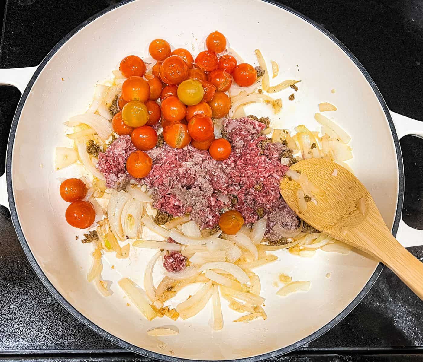 Sauteeng onion, garlic, tomatoes and meat in a skillet over medium heat.