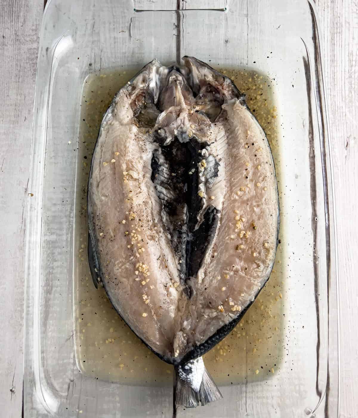 Marinating daing na bangus with vinegar, garlic, salt and pepper.